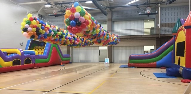 Inflatables inside gym including large obstacle course, slide, and bouncy castle